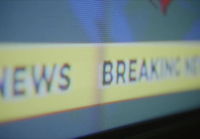 A banner runs across the television
