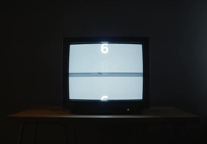 The television is flickering in the dark room