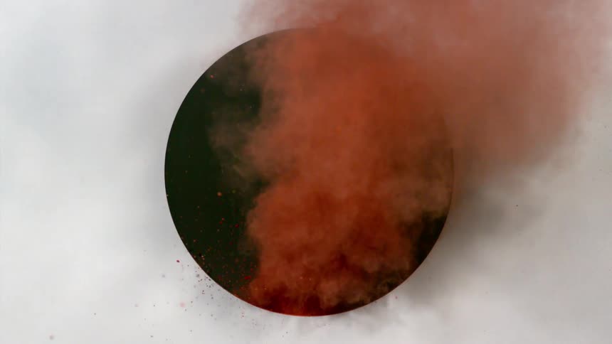 Red powder flies through a circular opening