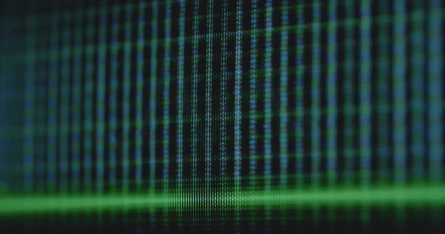 Macro shot of digital pixelated green trading line graph from an online finance application shifts up and down with the global economy in times of financial instability as it moves across the black screen of a flickering vintage tube TV