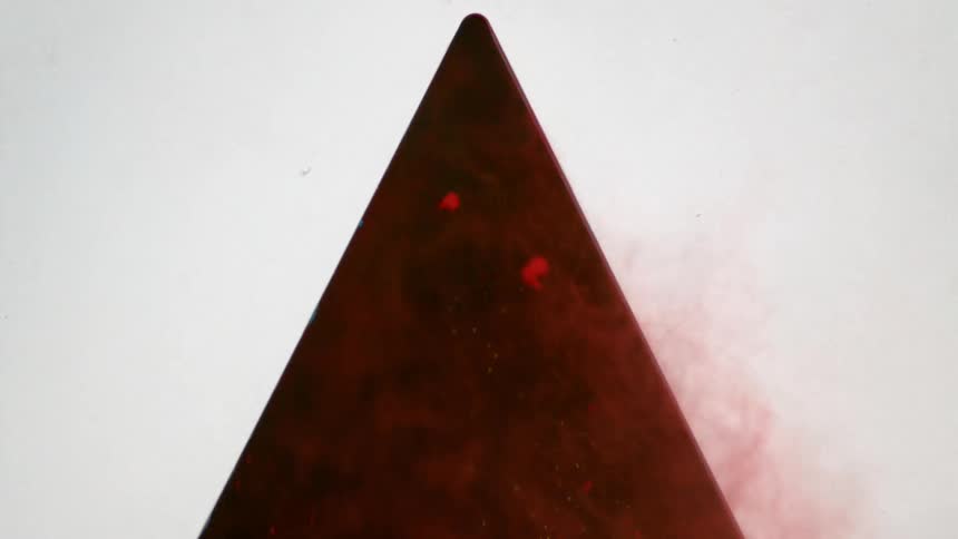 Red dirt pours out of a black triangle