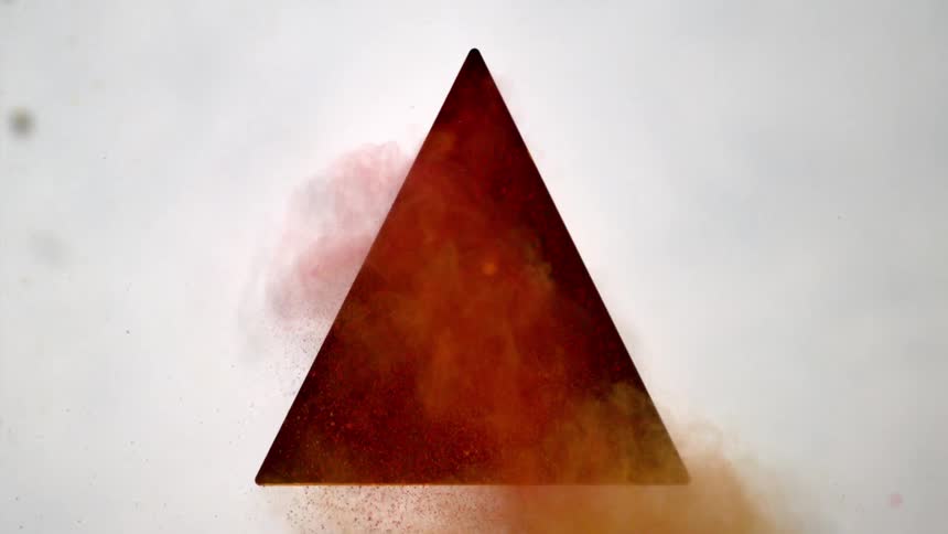 Yellow and red powder shooting out of triangular hole in wall