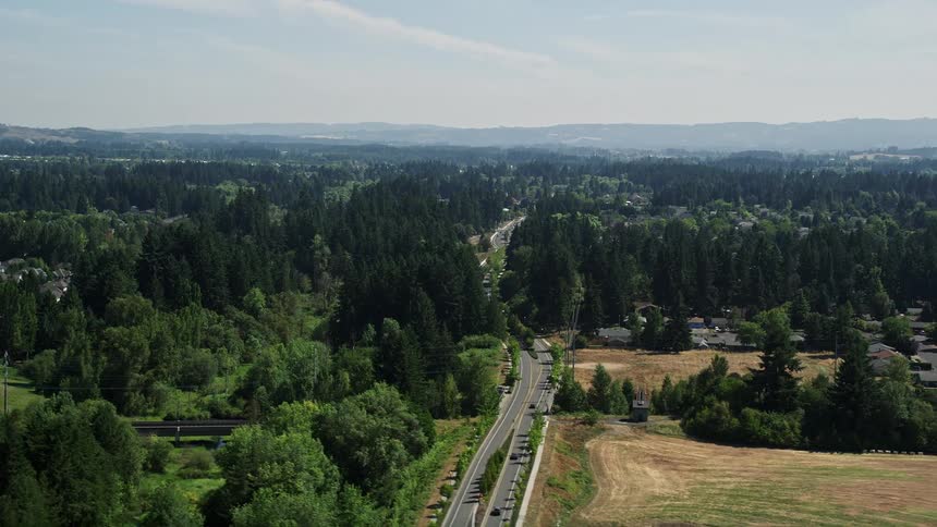 A sunny daytime aerial view of a residential road in a suburban neighborhood in Hillsboro Oregon surrounded by trees