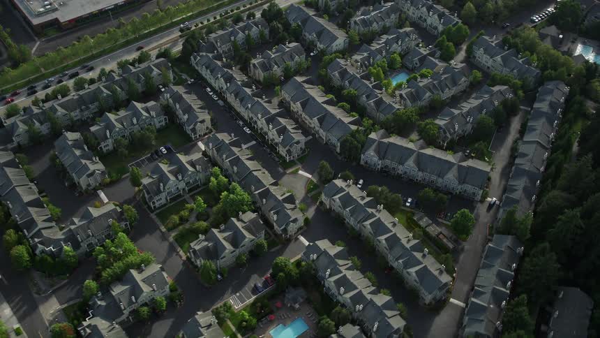 Approaching aerial view of apartment buildings in Hillsboro Oregon with a bird's eye perspective showcasing the residential neighborhood on a sunny day