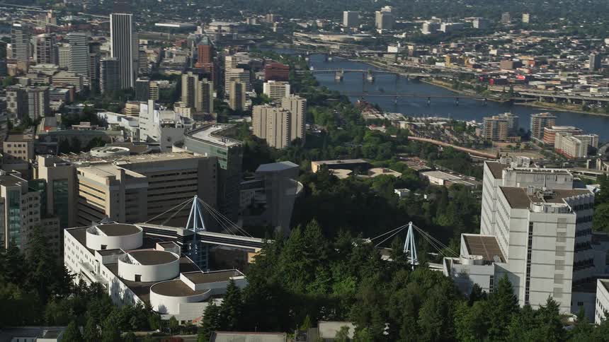 Aerial footage of Downtown Portland Oregon showcasing the cityscape with high-rise buildings and skyscrapers next to a river during daytime