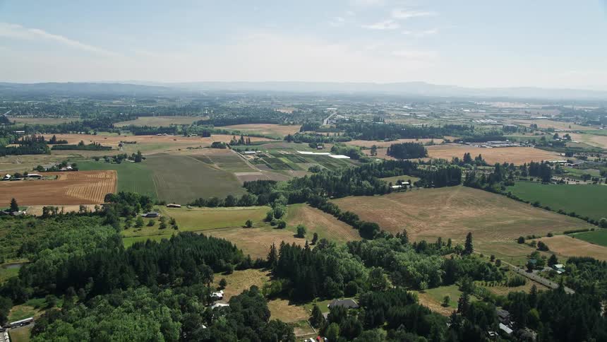 Fly over farmland pastures and fields in Hillsboro Oregon during sunny daytime showcasing the rustic and agricultural landscape of the Pacific Northwest