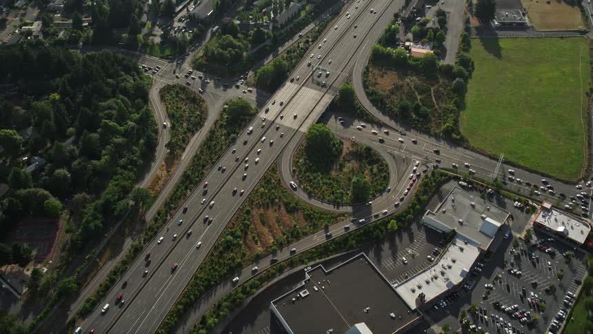 Aerial footage showcasing light traffic on a highway surrounded by buildings and vegetation during the daytime in Southwest Portland Oregon