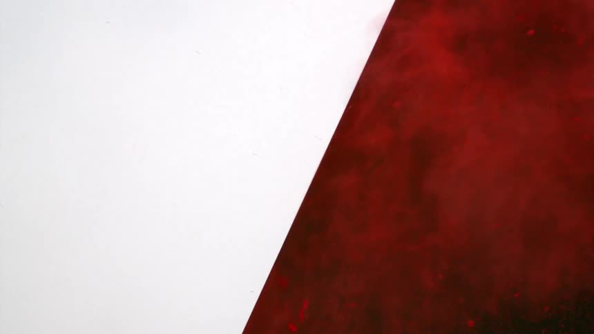Red powder shooting out from behind a white wall