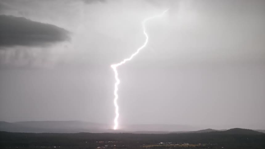 Lightning strike creates glow on side of hill on the horizon
