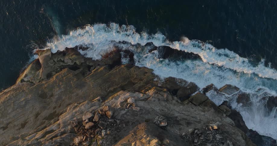 Waves splash against rocks along the coast as they roll into shore