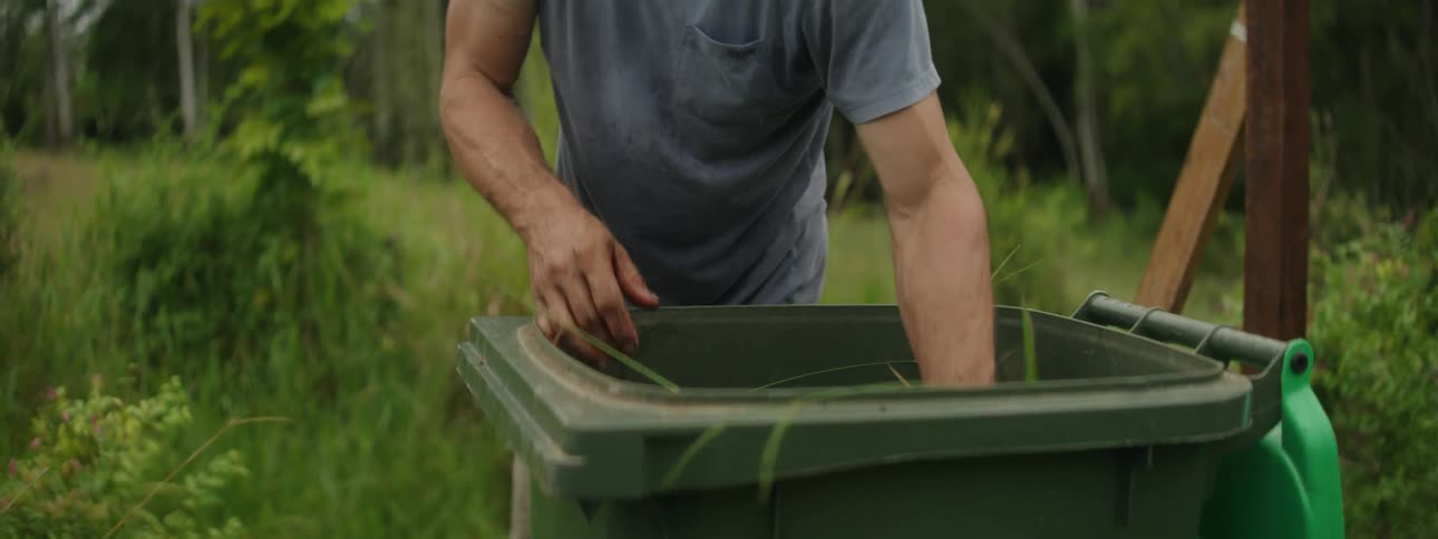 A man stirring a container full of weeds