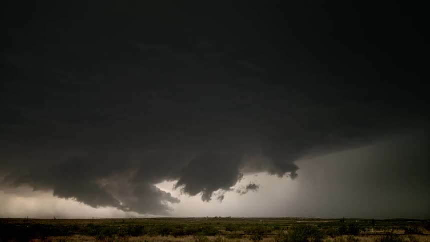 Large gray storm clouds with lightning bolts striking out of the sky onto the flat land below