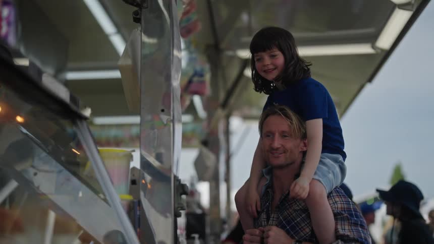 Smiling father with his daughter on his shoulders pointing at something