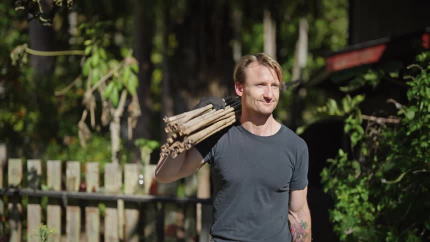 Blond man carrying wood on his shoulder
