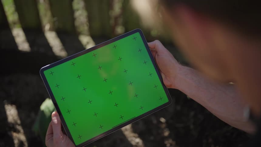A man sitting down outdoors looking at a tablet