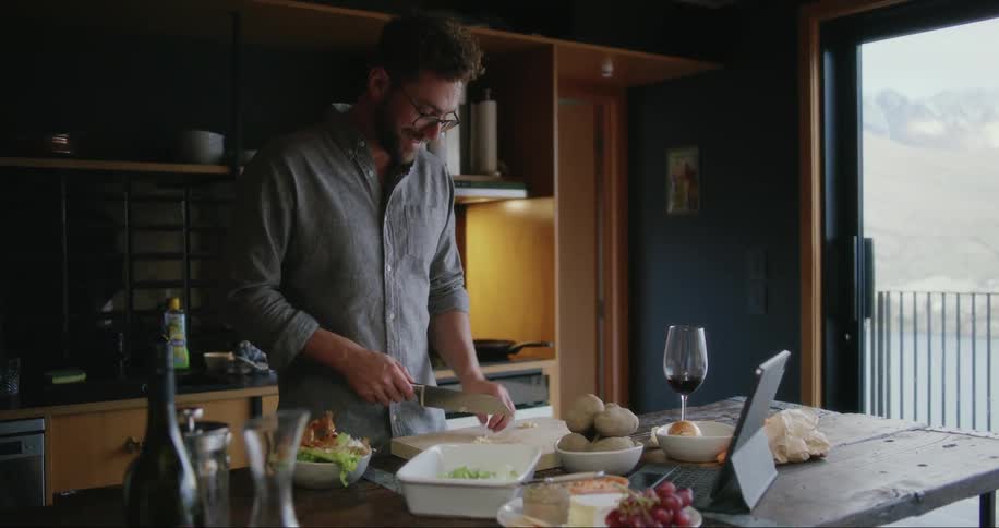 Man talking to someone over laptop while cooking
