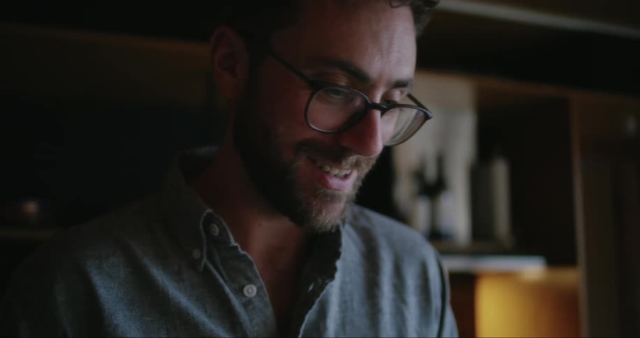 A man looks forward to talk to someone and laughs and turns his gaze down to continue the action he is doing