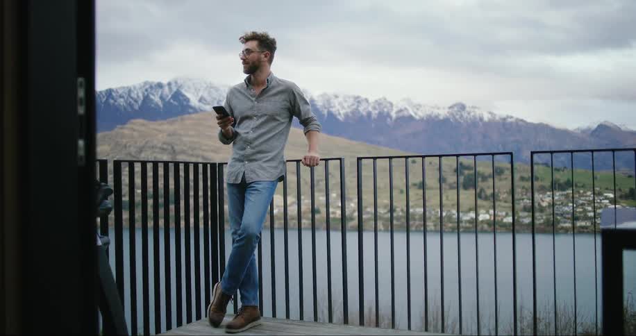 A man is checking his phone on the balcony