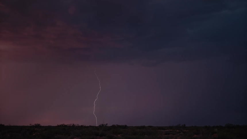 Lightning striking down on a silhouette horizon at night