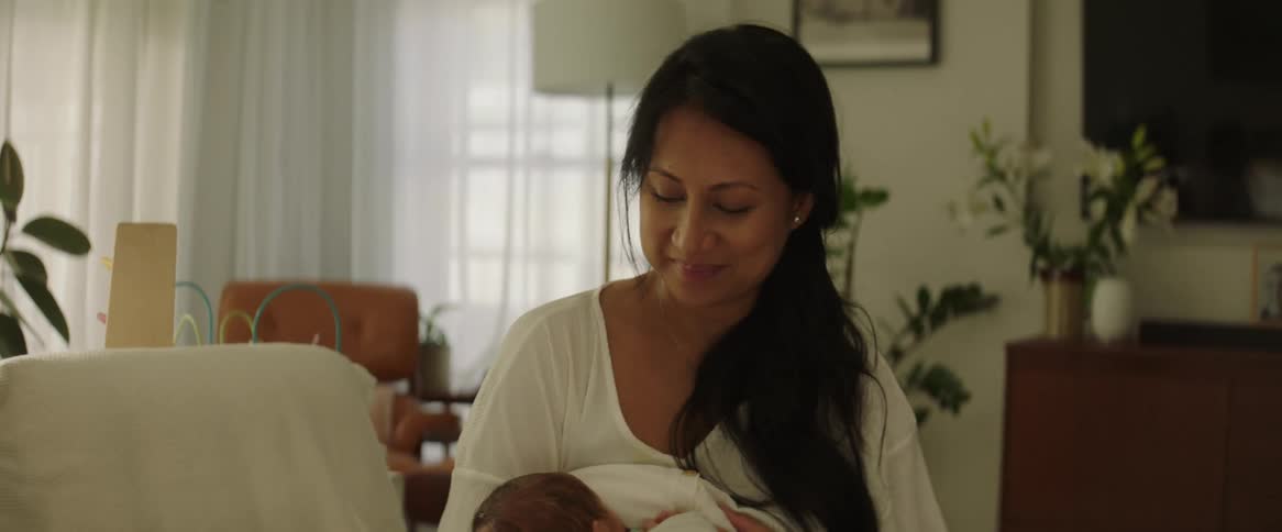 Mother sitting on the couch breastfeeding her baby