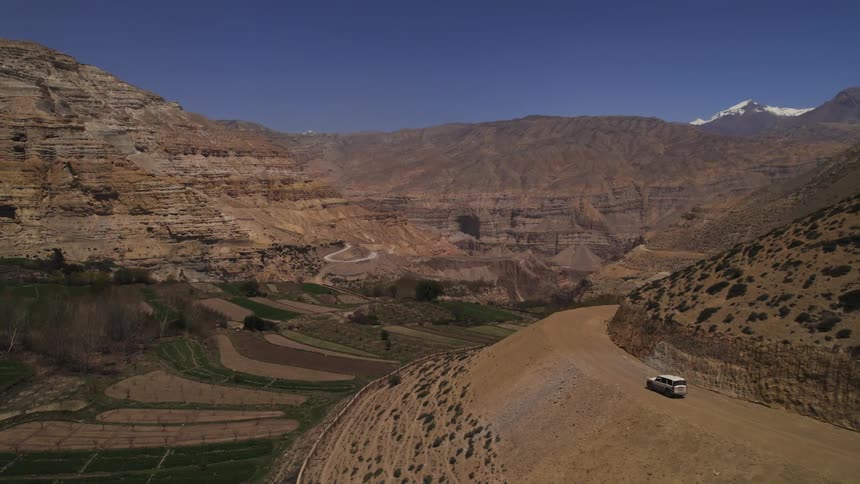 An aerial view of a car in a road in the desert with mountains