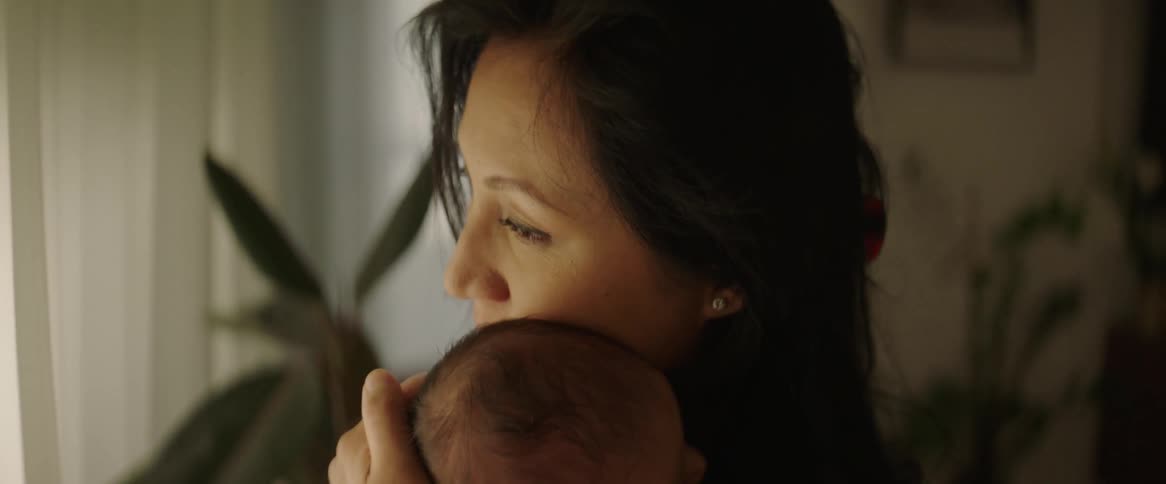 A mother taps her babys back as she rocks him