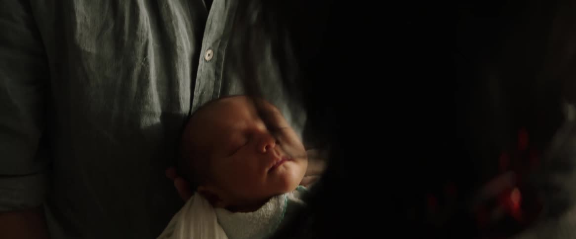A couple rocks their newborn child to sleep between them