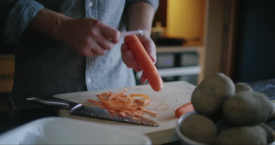 A man peeling vegetable inside the kitchen