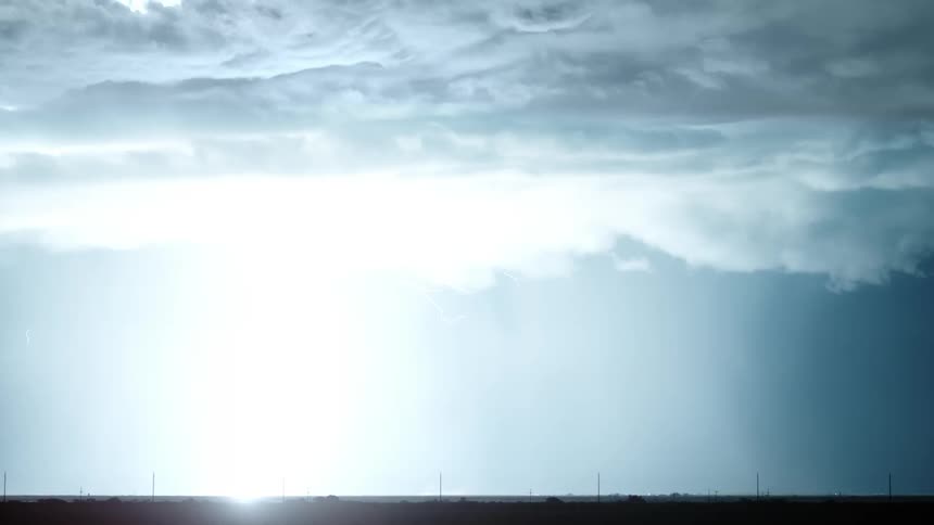 Lightning striking down in the middle of a dark night sky lighting up the ground below