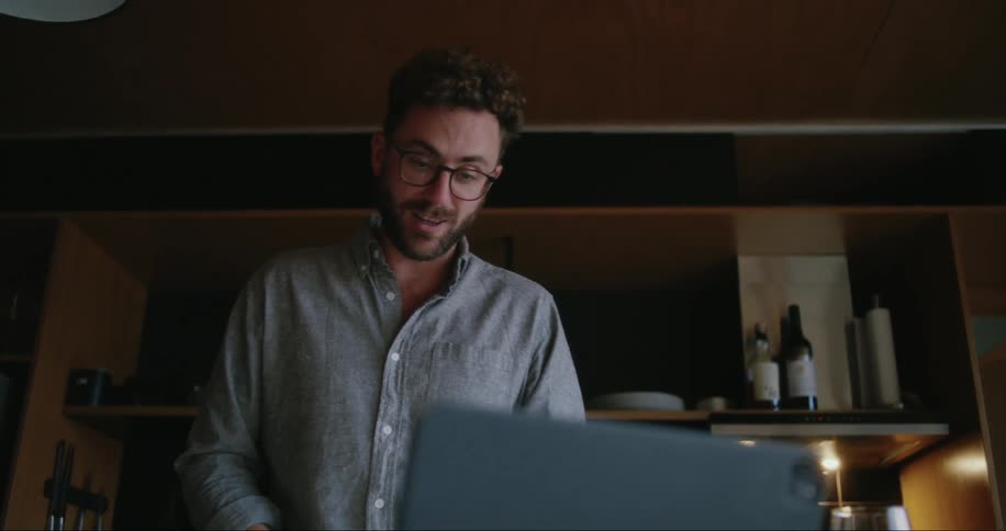A man doing something with his hands while smiling looking at his notebook