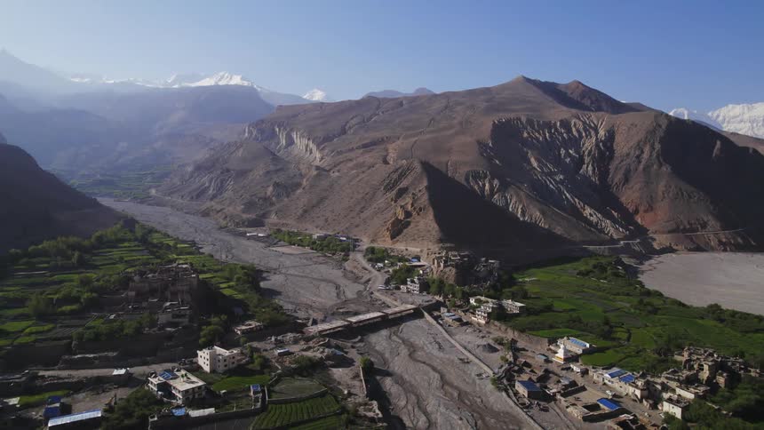 A small village next to a mountain and a dry river bed