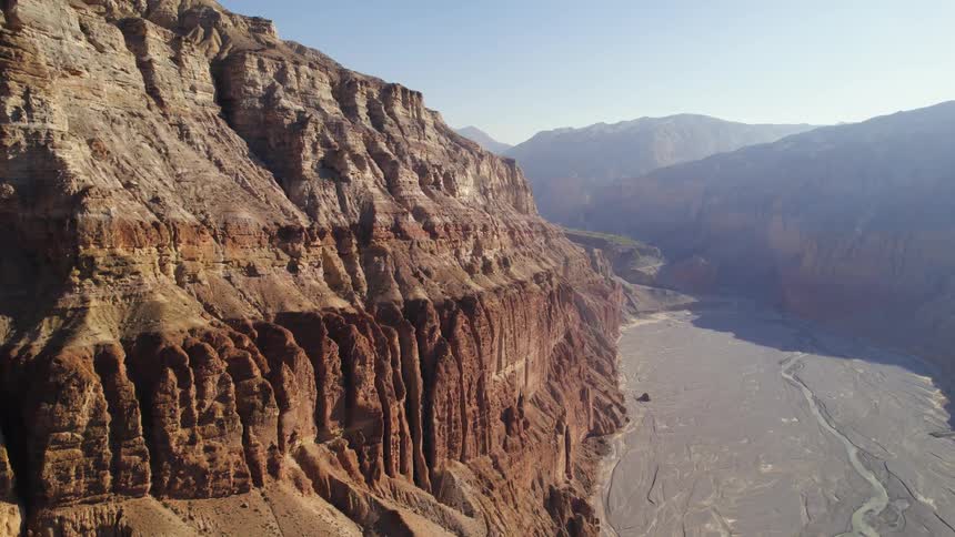 Aerial of a large rocky mountain with tall cliffs and a valley at the bottom