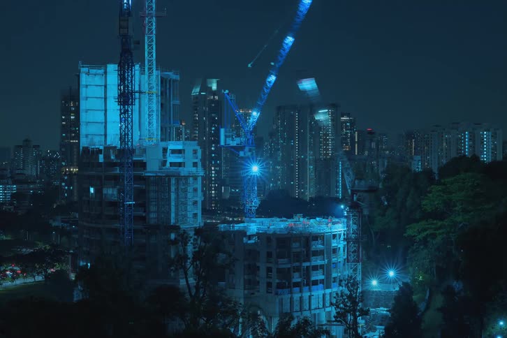 Construction cranes build skyscrapers in downtown at night