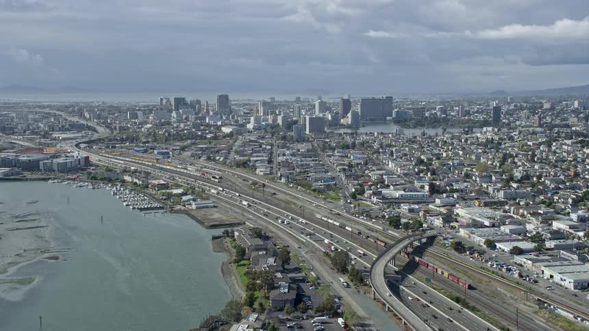  aerial footage of cars driving on the 880 freeway towards downtown Oakland in California showcasing the city's skyline and bustling transportation
