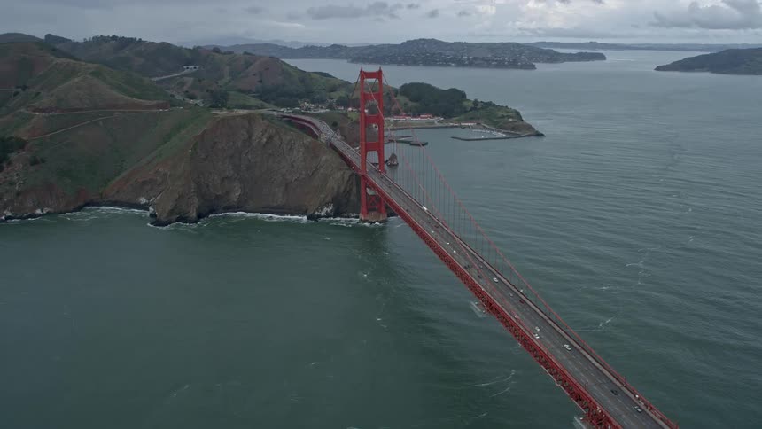 Aerial view of the iconic Golden Gate Bridge Marin side with cloudy skies and cars crossing over in San Francisco California
