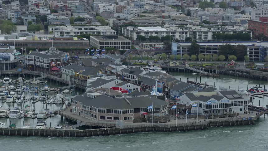 Aerial footage of flying by Pier 39 in San Francisco California showcasing the iconic structure and bustling cityscape of the bay area
