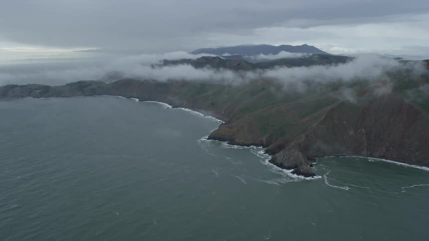 Approaching fog-wreathed coastal cliffs in Marin Headlands California during the day showcasing the epic beauty of the shoreline and cloudy skies
