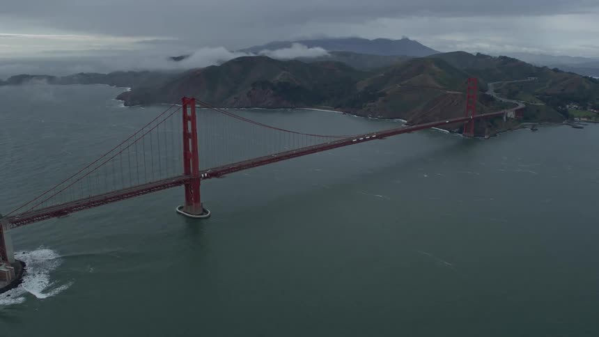 Aerial footage of an approaching cloudy day flying towards the iconic Golden Gate Bridge in San Francisco California