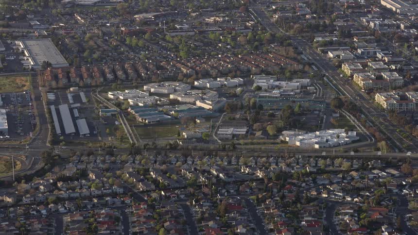  aerial footage of a reverse view of a prison complex in Milpitas California showcasing the government building set against partly cloudy skies in the South Bay Area