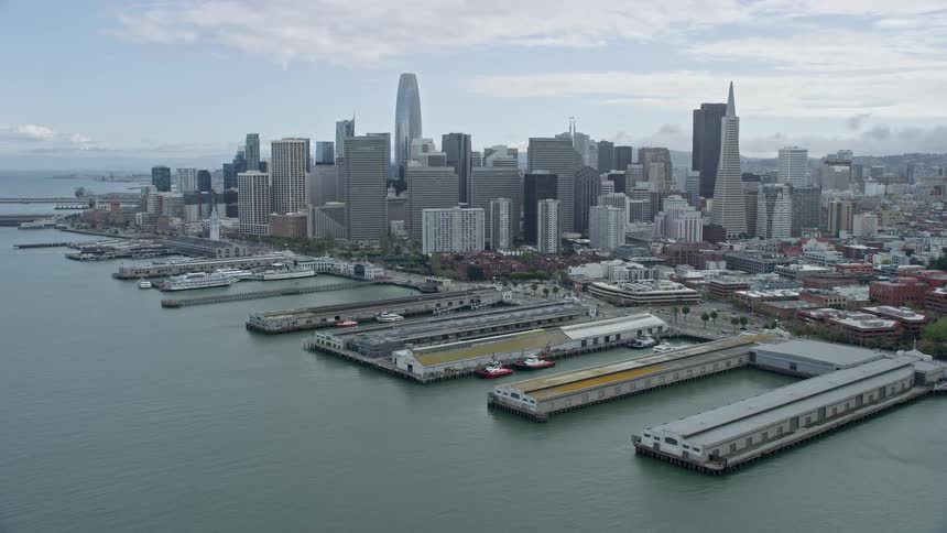 anaerial view of the San Francisco skyline and bustling piers in California showcasing towering skyscrapers and a cruise ship docked in the harbor