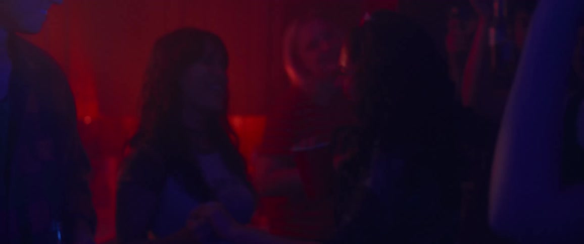 Two ladies having fun and dancing in a lowlight room illuminated by red light