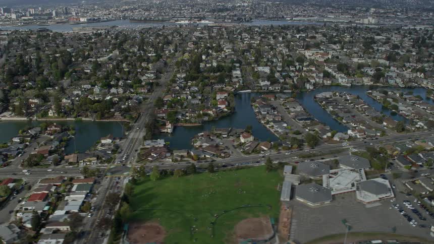  aerial footage showcasing waterfront homes in Alameda California with a river weaving through the suburban neighborhood on a partly cloudy day