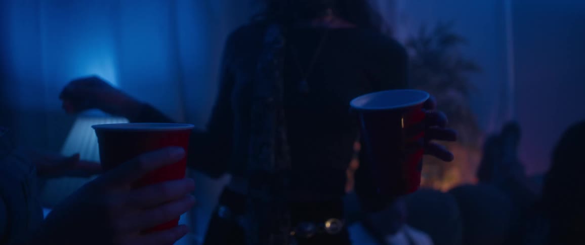 Two friends have drinks while dancing at a party on a blue room