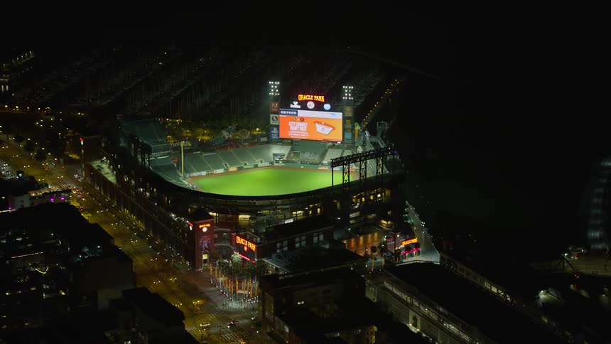 Aerial footage of Oracle Park baseball stadium at night in San Francisco California showcasing the city lights and vibrant atmosphere of the game