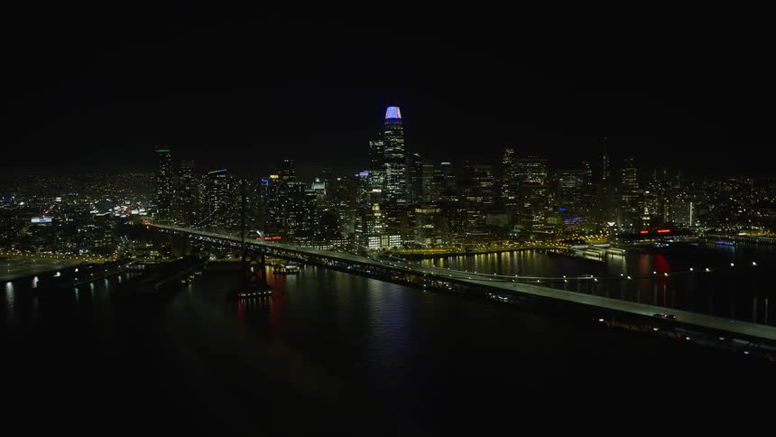 A stunningaerial view of the Bay Bridge and Downtown San Francisco skyline at night showcasing the city's high rises clear skies and the beautiful San Francisco Bay captured during a summer night in California's Bay Area