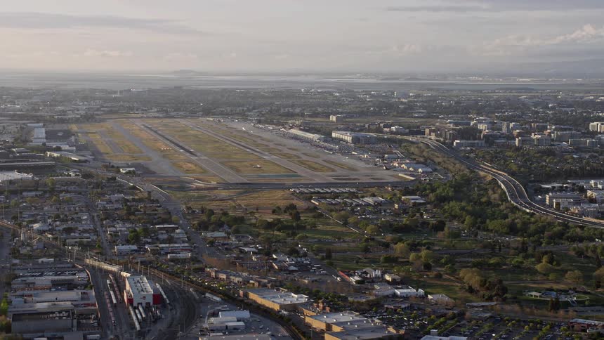 Aerial footage of San Jose International Airport at sunset showcasing the airfield amidst a suburban area with houses and businesses in the Bay Area California