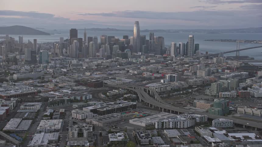 Breath-taking aerial footage capturing the vibrant San Francisco skyline at sunset as the camera tilts up from the South of Market neighborhood showcasing the city's high-rise buildings and urban residential areas against a backdrop of partly cloudy skies