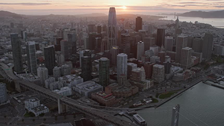  aerial footage of Downtown San Francisco at sunset showcasing the high-rise towers and skyscrapers against a partly cloudy sky in this epic cinematic shotover clip