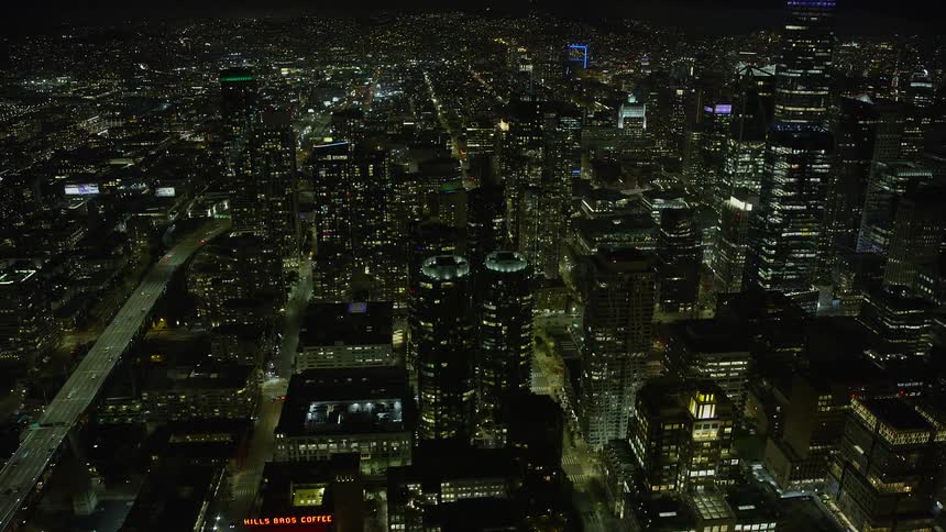  aerial footage of Downtown San Francisco skyscrapers near Bay Bridge at night showcasing the high rises and clear skies of the city in Northern California with a POV approach towards the superstructures