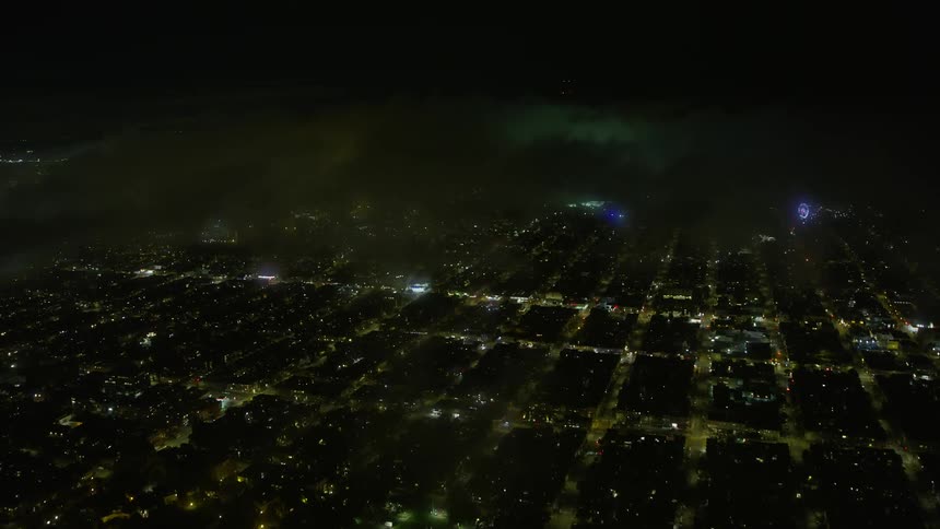 Approach the Inner Richmond District at night with fog overhead capturing the urban residential neighborhood and its illuminated skyline in thisaerial stock footage of San Francisco California
